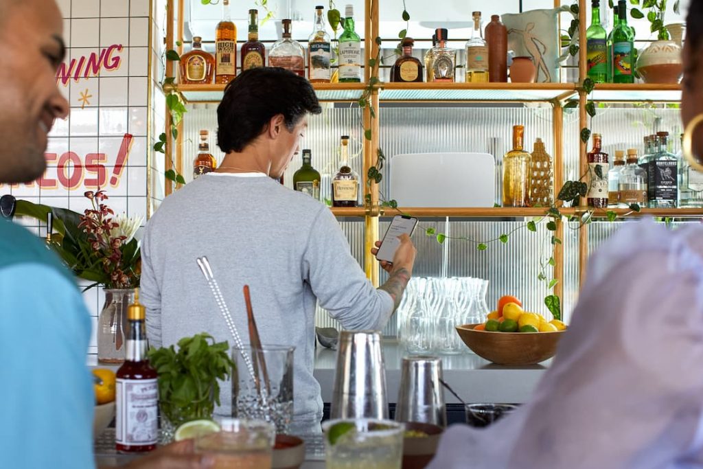 A cozy cafe with a Sonos white Five speaker mounted on the shelf, providing background music for customers.