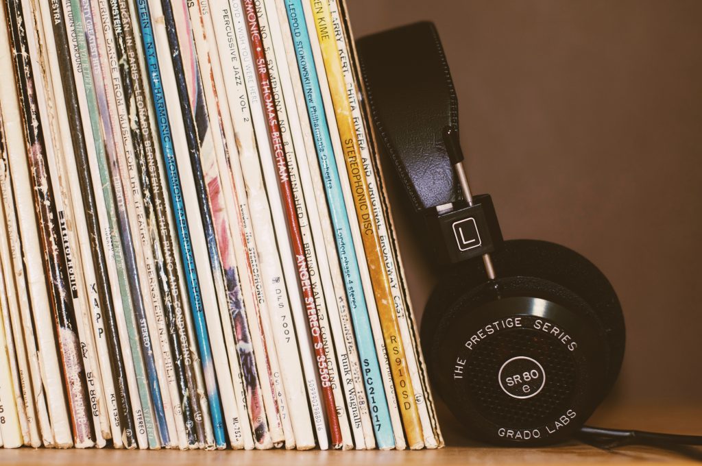 A pair of headphones rests against a stack of vinyl records.
