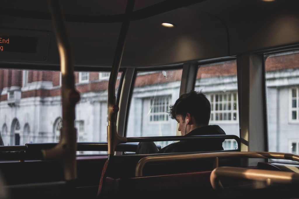 A music listener is shown in the front seat of a van, with both headphones in.