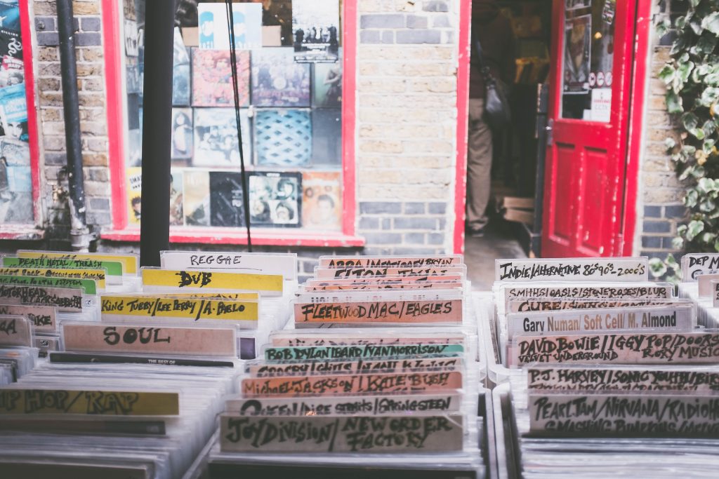 A brightly lit record store is displayed, with rows of records, labeled by genre
