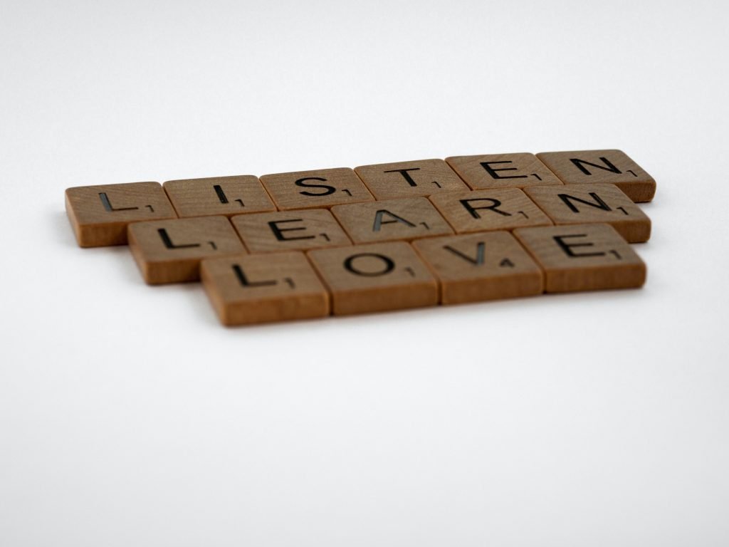 Wooden letters are arranged to create the phrase "Listen, Learn, Love"