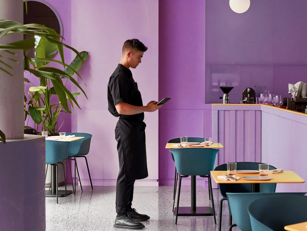 staff member in the middle of the restaurant making music adjustments from a smartphone